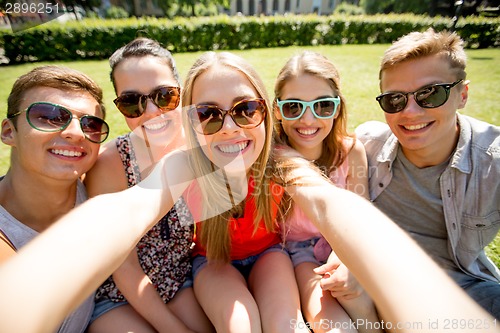 Image of group of smiling friends making selfie in park