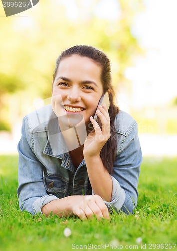 Image of smiling young girl with smartphone lying on grass