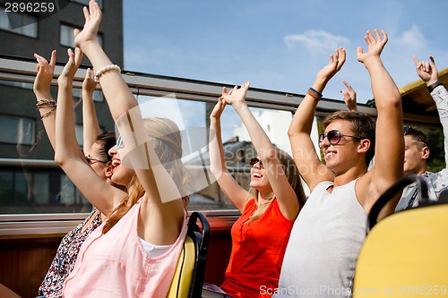 Image of group of smiling friends traveling by tour bus