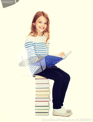 Image of little student girl sitting on stack of books