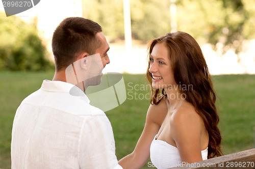 Image of smiling couple sitting on bench in park