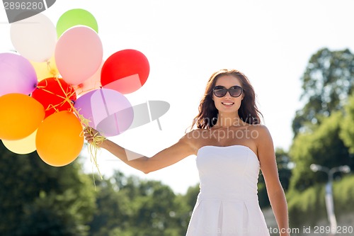 Image of smiling young woman in sunglasses with balloons