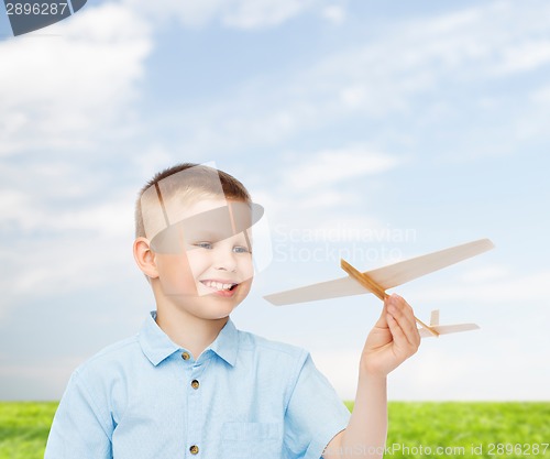 Image of smiling little boy holding a wooden airplane model