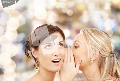 Image of two smiling women whispering gossip