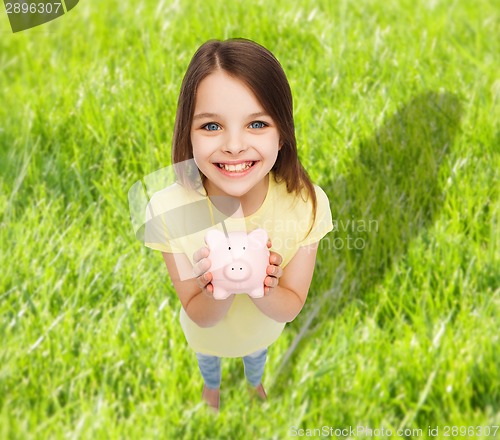 Image of beautiful little girl with piggy bank