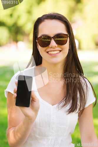 Image of smiling young girl with smartphone outdoors