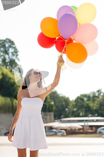 Image of smiling young woman in sunglasses with balloons