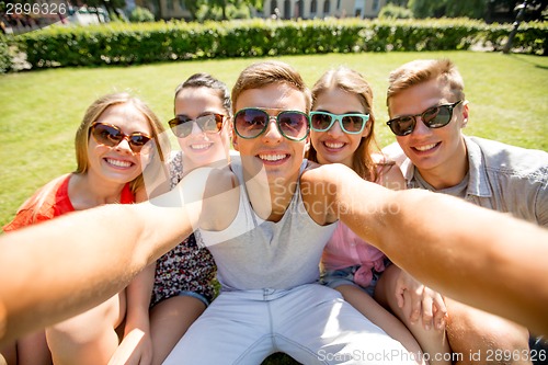 Image of group of smiling friends making selfie in park