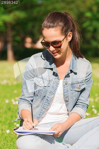 Image of smiling young girl with notebook writing in park