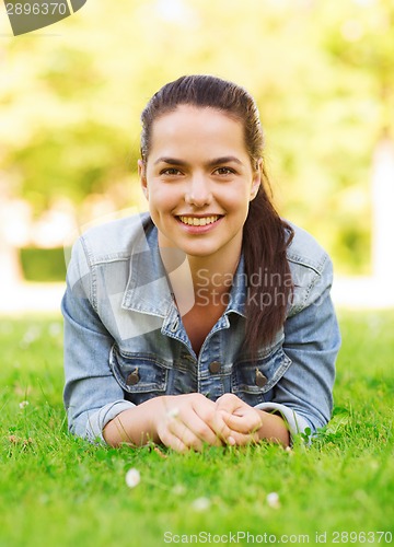 Image of smiling young girl lying on grass