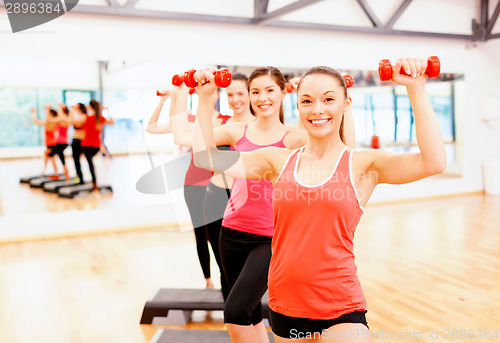 Image of group of smiling female with dumbbells and step