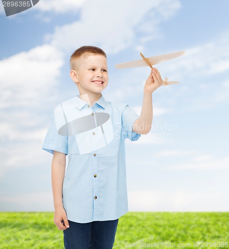 Image of smiling little boy holding a wooden airplane model