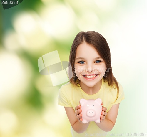 Image of beautiful little girl with piggy bank
