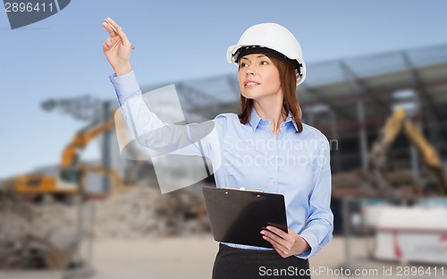 Image of smiling businesswoman in helmet with clipboard