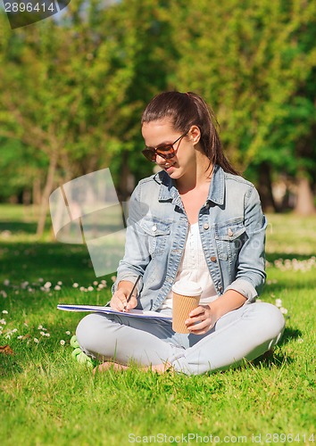 Image of smiling young girl with notebook and coffee cup