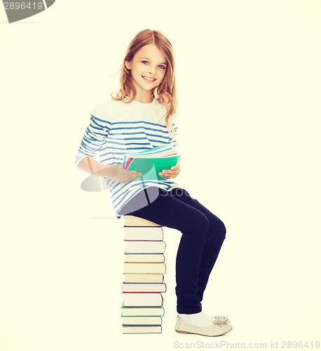 Image of little student girl sitting on stack of books