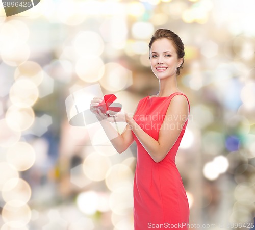 Image of smiling young woman in red dress with gift box