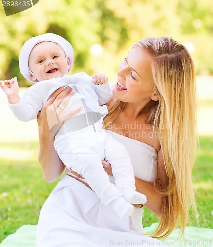 Image of happy mother with little baby sitting on blanket