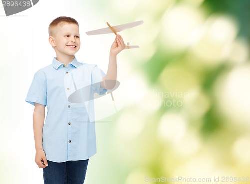 Image of smiling little boy holding a wooden airplane model