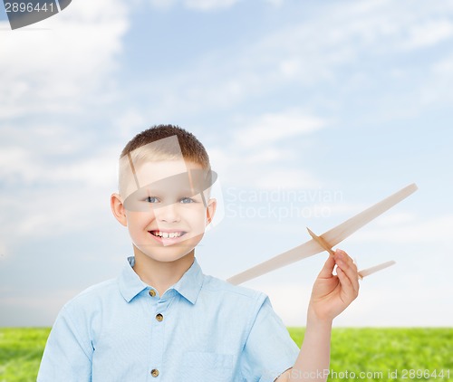 Image of smiling little boy holding a wooden airplane model