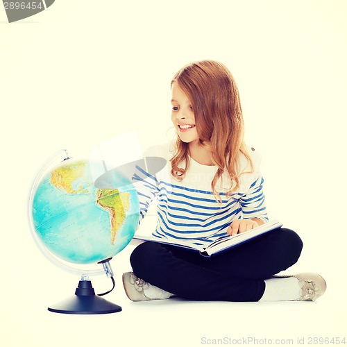 Image of child looking at globe and holding book