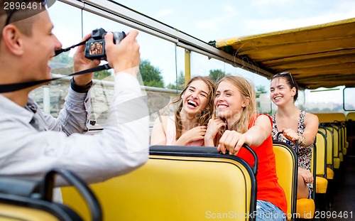 Image of laughing friends with camera traveling by tour bus