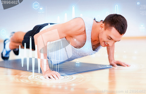 Image of smiling man doing push-ups in the gym