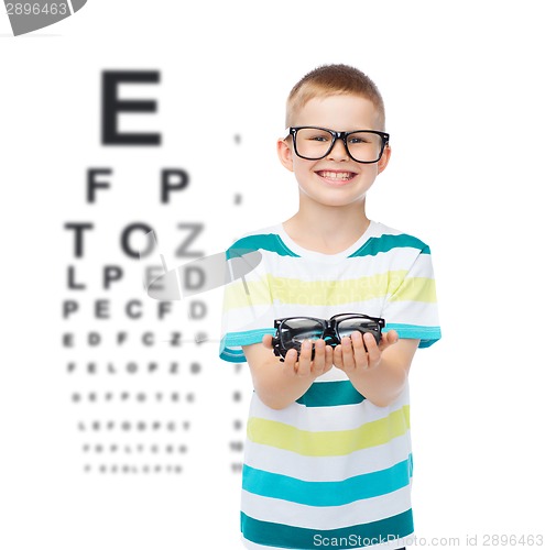 Image of smiling boy in eyeglasses holding spectacles