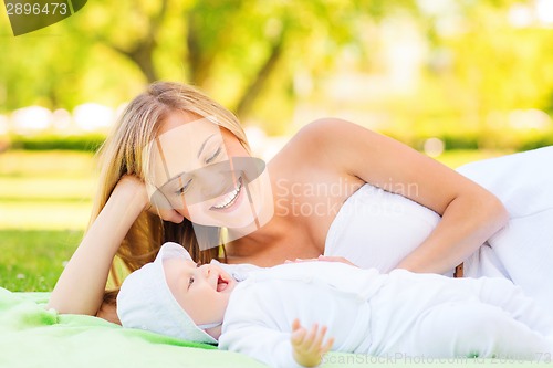 Image of happy mother lying with little baby on blanket