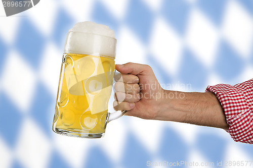 Image of Man in traditional Bavarian shirt holds mug of beer