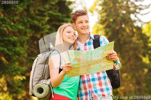 Image of smiling couple with map and backpack in forest
