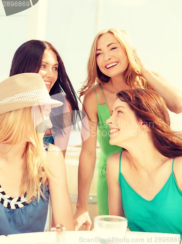 Image of group of smiling girls in cafe on the beach