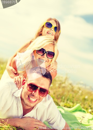 Image of smiling family in sunglasses lying on blanket