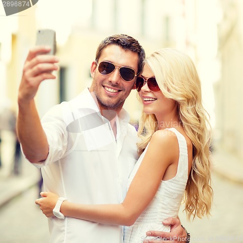 Image of smiling couple taking selfie with smartphone