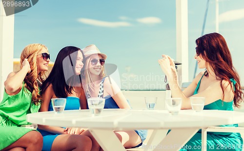 Image of girls taking photo in cafe on the beach