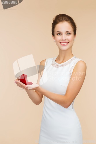 Image of smiling woman holding red gift box with ring