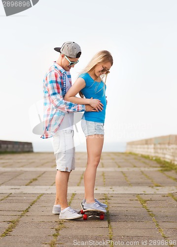 Image of smiling couple with skateboard outdoors