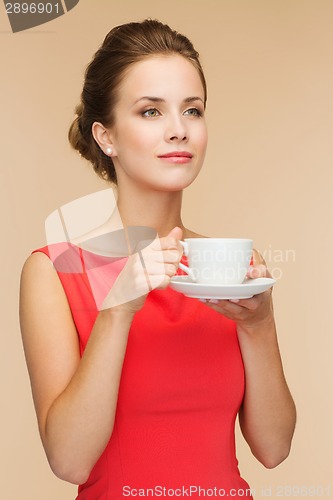 Image of smiling woman in red dress with cup of coffee