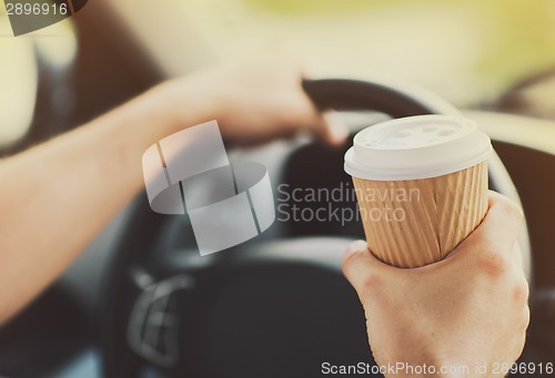 Image of man drinking coffee while driving the car