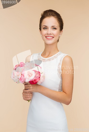 Image of smiling woman in white dress with bouquet of roses