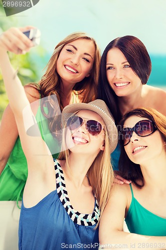 Image of girls taking photo in cafe on the beach