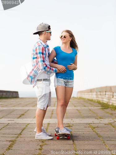 Image of smiling couple with skateboard outdoors