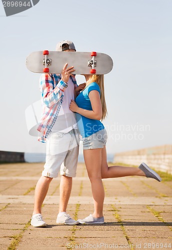 Image of couple with skateboard kissing outdoors