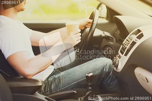 Image of man drinking coffee while driving the car