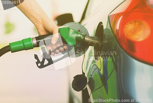 Image of man pumping gasoline fuel in car at gas station