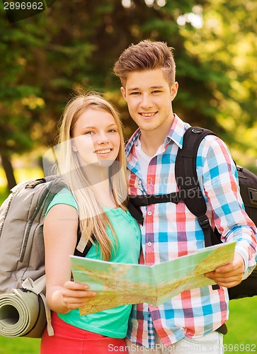 Image of smiling couple with map and backpack in forest
