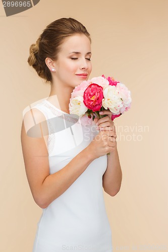 Image of smiling woman in white dress with bouquet of roses