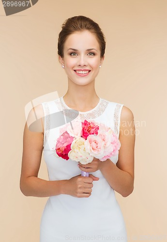 Image of smiling woman in white dress with bouquet of roses