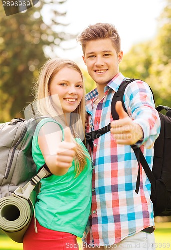 Image of smiling couple with backpacks showing thumbs up