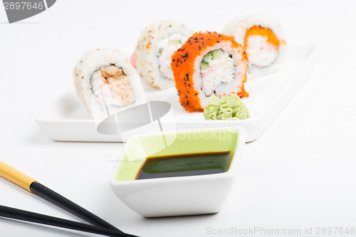 Image of Focus on soy sauce, shushi rolls in back